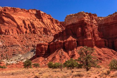 Arka planda mavi gökyüzü olan kayalık bir dağ sırası. Dağlar kırmızı ve kahverengidir, gökyüzü açık ve mavidir. Huzurlu ve huzurlu bir sahne.