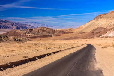 Arka planda mavi gökyüzü olan çölde bir yol. Yol boş ve gökyüzü temiz.