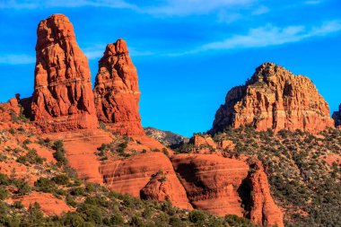Arka planda mavi gökyüzü olan güzel bir dağ sırası. Dağlar kızıl kayadan oluşmuş, sahneye sıcak ve davetkar bir atmosfer katıyor. Canlı kırmızı kayaların birleşimi.