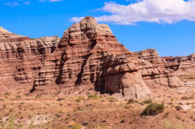 Arka planda açık mavi gökyüzü olan kayalık bir dağ sırası. Dağlar kahverengi ve kayalık, gökyüzü parlak ve berrak