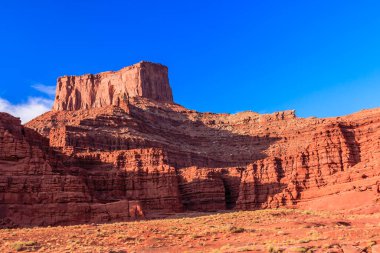 Arka planda mavi gökyüzü olan kayalık bir dağ sırası. Dağ, aralarında küçük, kayalık bir vadi bulunan büyük, kayalık bir tepedir. Gökyüzü açık ve mavi, görünürde bulut yok.