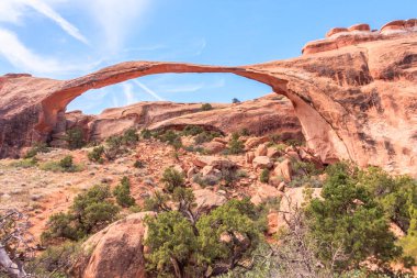 A bridge spans a canyon with a clear blue sky above. The bridge is arched and spans the width of the canyon. The canyon is rocky and barren, with sparse vegetation clipart