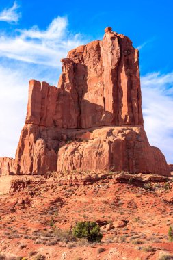 Çöldeki bir yamaçta büyük bir kaya oluşumu bulunur. Gökyüzü açık ve mavidir, ve güneş parlıyor. Huzurlu ve huzurlu bir sahne.