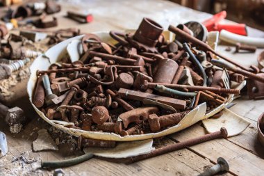 Masadaki paslı vida ve cıvata yığını. Sahne biraz kaotik ve düzensiz.