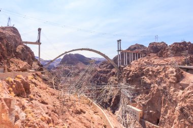 Altında nehir akan derin bir kanyon üzerine büyük bir köprü inşa ediliyor. Köprü bir dağın üzerine inşa ediliyor, bu da projenin etkileyici boyutunu arttırıyor.