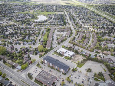 Büyük bir apartman kompleksi ve otoparkı olan bir yerleşim yeri. Otopark araba ve kamyonlarla dolu.