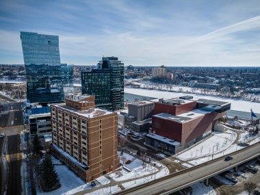 Merkezinde büyük bir bina ve içinden akan bir nehir olan şehir manzarası. Binalar yüksek ve gökyüzü temiz.