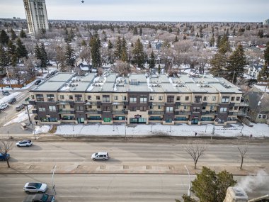 Bir sürü penceresi ve caddenin aşağısında birkaç arabası olan büyük bir apartman. Gökyüzü bulutlu ve kar yağıyor