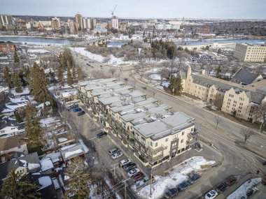 İçinden bir nehir akan karlı bir şehir manzarası. Binalar yüksek ve caddede park edilmiş bir sürü araba var.
