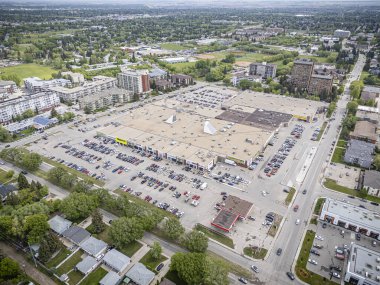 Bir sürü arabası ve bir kaç adamı olan büyük bir otopark. Otopark bir şehirde ve binalarla çevrili.
