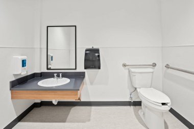 Lavabosu, tuvaleti ve aynası olan bir banyo. Tuvalet beyaz ve kapağı var.