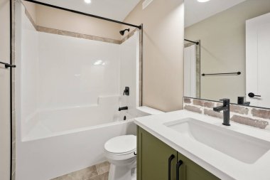 Yeşil dolabı ve beyaz lavabosu olan bir banyo. Lavabo bir tuvalet ve duşun yanında.