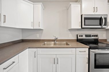 Beyaz sobası ve mikrodalgası olan temiz ve boş bir mutfak. Mutfak iyi düzenlenmiş ve kullanıma hazır.