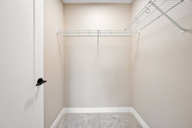 Siyah kapılı beyaz bir dolap. Dolap boş ve beyaz bir raf var. Kapı kapalı.