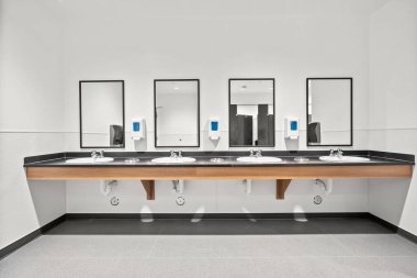 Umumi bir tuvalette bir sıra lavabo. Lavaboların hepsi boş. Aynalar siyah beyaz.