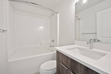 Beyaz tuvaleti ve lavabosu olan bir banyo. Banyo temiz ve bakımlı.