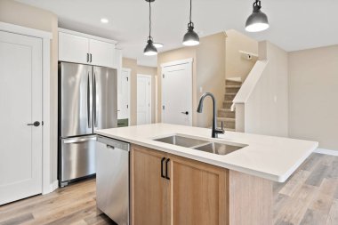 Paslanmaz çelik lavabosu ve gümüş bir buzdolabı olan bir mutfak. Mutfak temiz ve aydınlık.