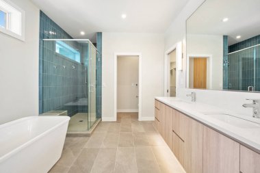 Beyaz küveti ve mavi duş kabini olan bir banyo. Duş kabininin cam kapısı var.