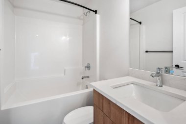 Beyaz tuvaleti ve lavabosu olan bir banyo. Banyo temiz ve bakımlı.