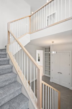 Ahşap korkuluklu ve beyaz halılı bir merdiven. Merdiven beyaz kapısı ve beyaz dolabı olan bir koridorda bulunuyor. Sahne temiz ve basit.