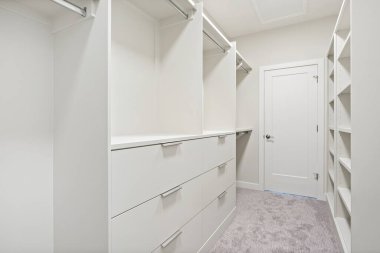 Dolapta raflar ve çekmecelerle beyaz bir yürüyüş. Dolap çok temiz ve düzenli. Kapı beyaz ve gümüş sapı var.