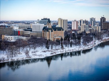 Altında nehir akan bir şehir ve arkasında büyük bir bina var. Şehir karla kaplı ve nehir sakin.