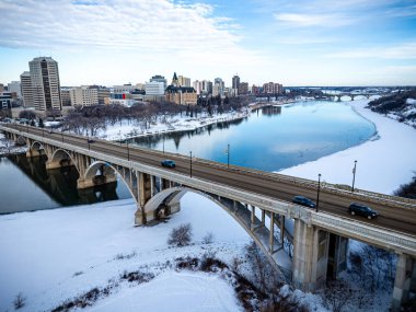 Nehrin üzerinde, yerde kar olan bir köprü. Köprü, nehrin genişliğini kapsayan büyük bir yapıdır. Yerdeki kar manzaraya huzur ve huzur veriyor.