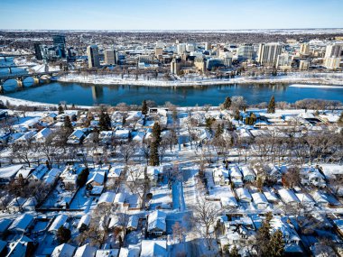 İçinden bir nehir akan karlı bir şehir manzarası. Evler karla kaplı ve sokaklar bomboş. Şehir karla kaplanırken manzara huzurlu ve huzurlu.