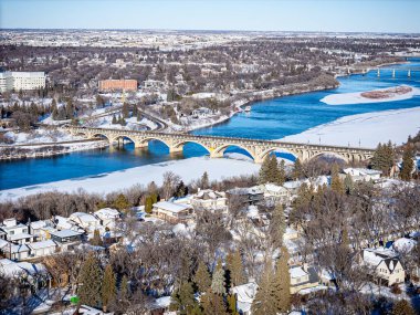 Nehir üzerinde köprüsü olan karlı bir şehir. Köprü ön planda görünen tek şey.