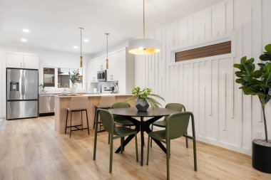 Yemek masası ve sandalyeleri olan bir mutfak. Masa yeşil sandalyelerle çevrili. Masanın üzerinde saksı çiçeği var.