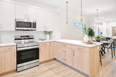 Beyaz sobası ve dolapları olan bir mutfak. Dolaplar kahverengi, soba gümüş. Mutfak temiz ve iyi düzenlenmiş.