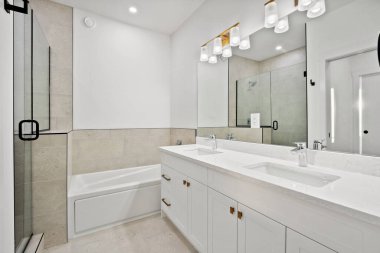 Banyo temiz ve iyi aydınlatılmış, lavabonun üzerinde büyük bir ayna var. Lavabonun iki lavabosu var ve küvet beyaz. Banyo modern ve zarif bir tasarıma sahip.