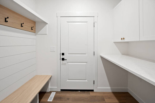 A white door with a bench in front of it. The bench is wooden and has a light brown color