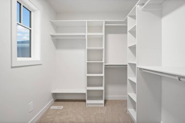 Penceresi ve bankı olan beyaz bir oda. Oda boş ve minimalist bir görünüşü var.