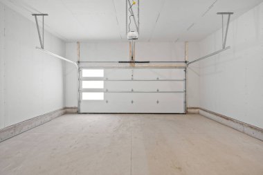 Beyaz kapısı ve garaj kapısı olan bir garaj. Garaj boş ve minimalist bir görünüşü var.