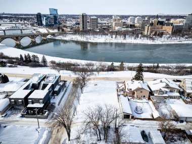 İçinden bir nehir akan karlı bir şehir manzarası. Evler küçük ve sokaklar boş.