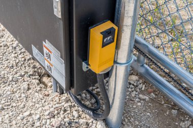 Üzerinde sarı bir kutu olan kara kutu. Kutu metal bir direğe bağlı.