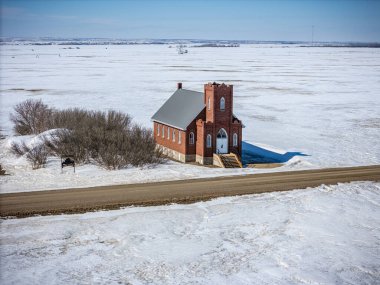 Küçük kırmızı kilise karlı bir tarlanın ortasında duruyor. Kilise toprak bir yol ve birkaç ağaçla çevrilidir. Ortalık sakin ve sakin, kar zemini kaplıyor.