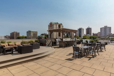 Şehir manzaralı bir çatı terası var. Veranda masa ve sandalyelerle dolu ve bir ızgara ve bir bar var. Atmosfer rahat ve davetkar.