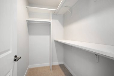 Kapısı ve rafları olan beyaz bir dolap. Dolap boş ve minimalist bir görünüşü var.