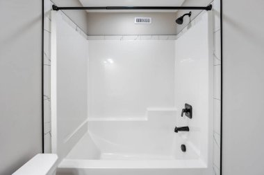 Siyah duş başlığı ve beyaz küveti olan beyaz bir banyo. Duş başlığında 16 yazıyor.