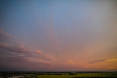 Açık mavi gökyüzü ile güzel bir gün batımı. Gökyüzü bulutlarla dolu ve güneş batıyor.