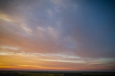 Açık mavi gökyüzü ile güzel bir gün batımı. Gökyüzü bulutlarla dolu ve güneş batıyor.