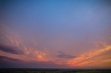 Gökyüzü, birkaç bulutun etrafa saçıldığı güzel bir mavi tondur. Güneş batıyor, sıcak ve huzurlu bir atmosfer yaratıyor.