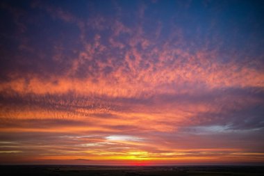 Pembe ve turuncu gökyüzü ile güzel bir gün batımı. Gökyüzü bulutlarla dolu ve güneş batıyor.