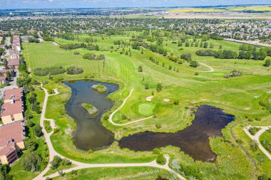 Arka planda golf sahası ve göleti olan bir golf sahası. Gölet çimenler ve ağaçlarla çevrili.