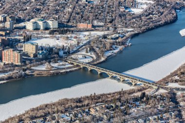 Üzerinden nehir akan ve üzerinde köprü olan bir şehir. Köprü büyüktür ve nehrin genişliğini kapsar. Şehir çoğunlukla karla kaplı, soğuk ve kış havası veriyor.
