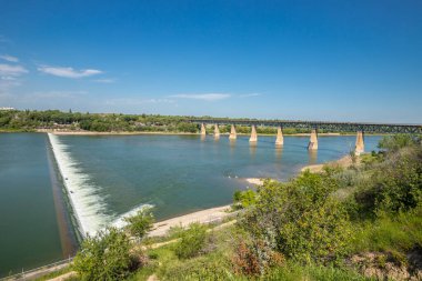 Arka planda köprü olan güzel bir nehir manzarası. Su sakin ve gökyüzü berrak.