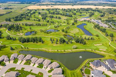 Göllü golf sahası ve arka planda evleri var. Golf sahası ağaçlar ve evlerle çevrili.