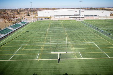 Ortasında bir futbol golü olan büyük bir saha. Alan bomboş. Gökyüzü mavi
